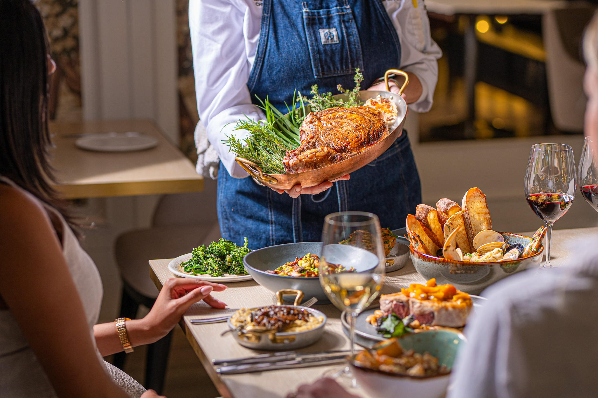 Chef holding a platter of food next to a table of brightly colored dishes.