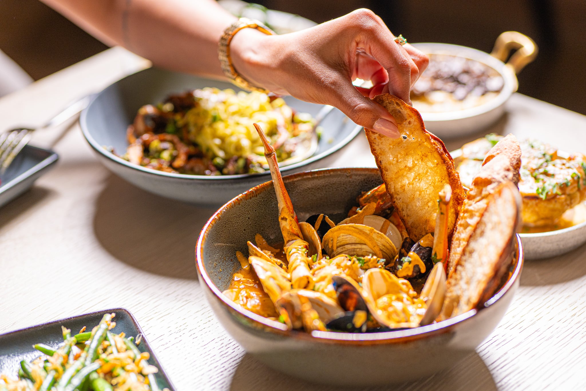 Women grabbing a piece of grilled toast from a bowl full of seafood at Santé Restaurant