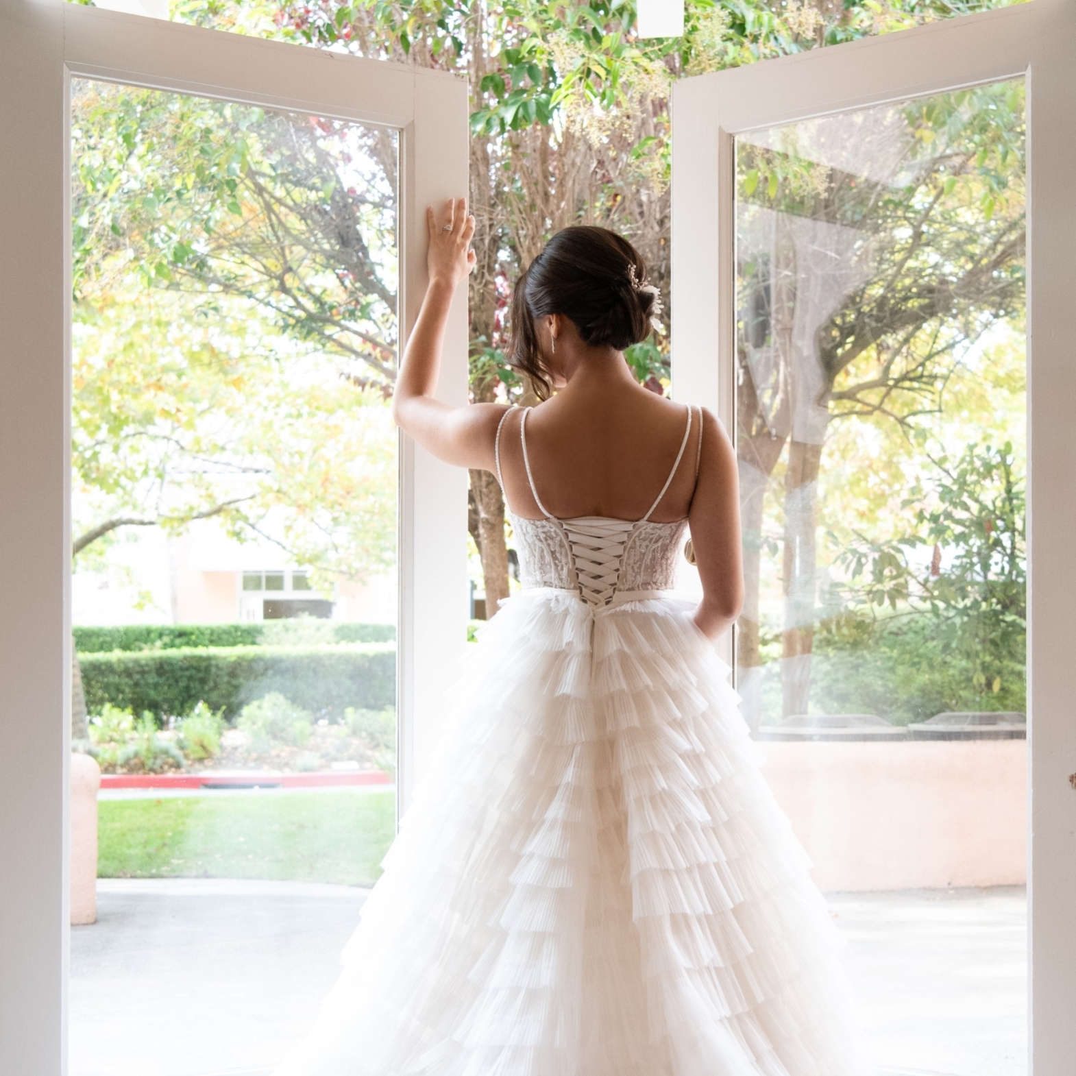 woman in wedding dress walking through french doors opening up to a patio