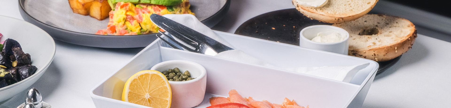 Plate of breakfast food with bagel, cream cheese, lox, scrambled eggs, and breakfast potatoes
