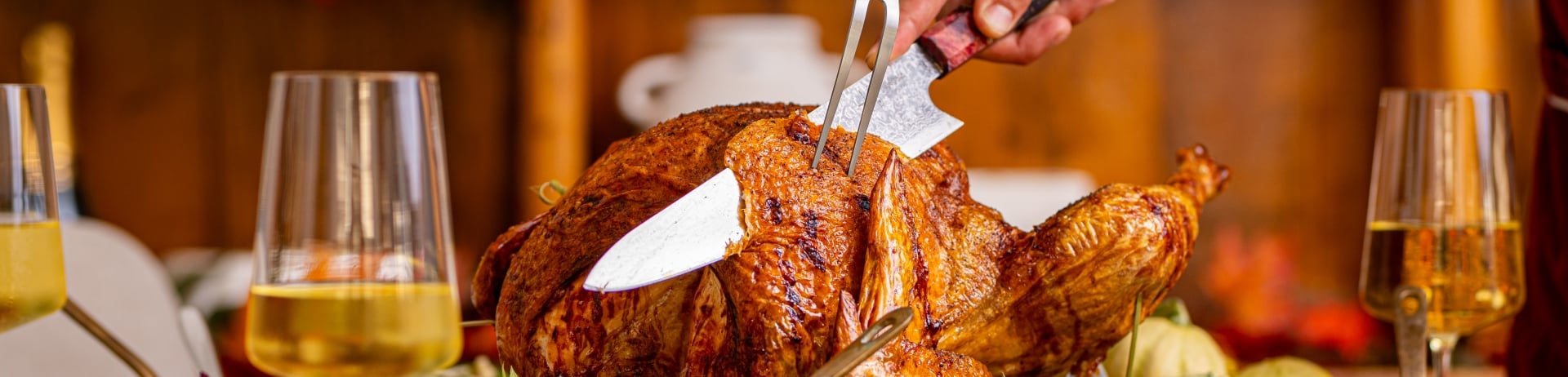 Chef carving a Thanksgiving turkey on a table full of festive food