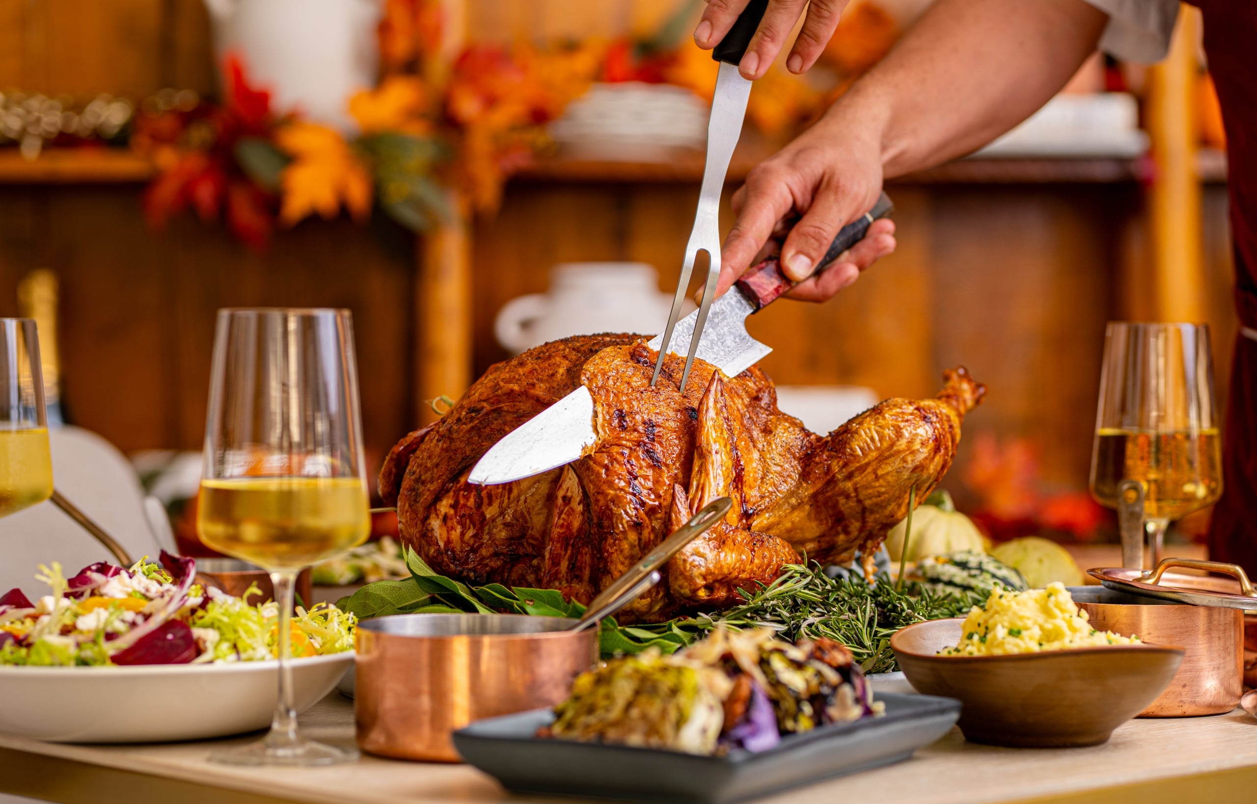 Chef carving a Thanksgiving turkey on a table full of festive food