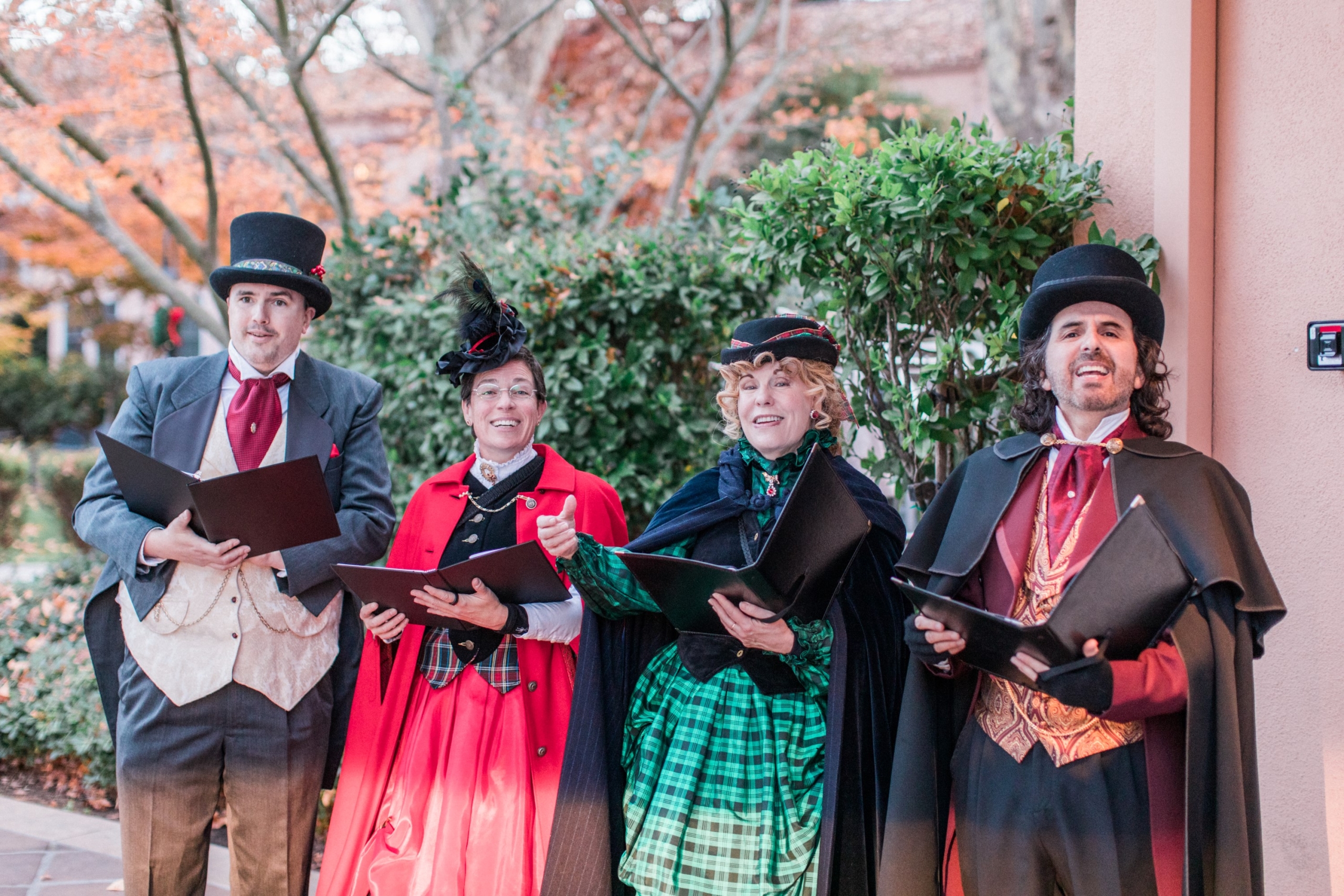 four christmas carolers dressed in festive attire