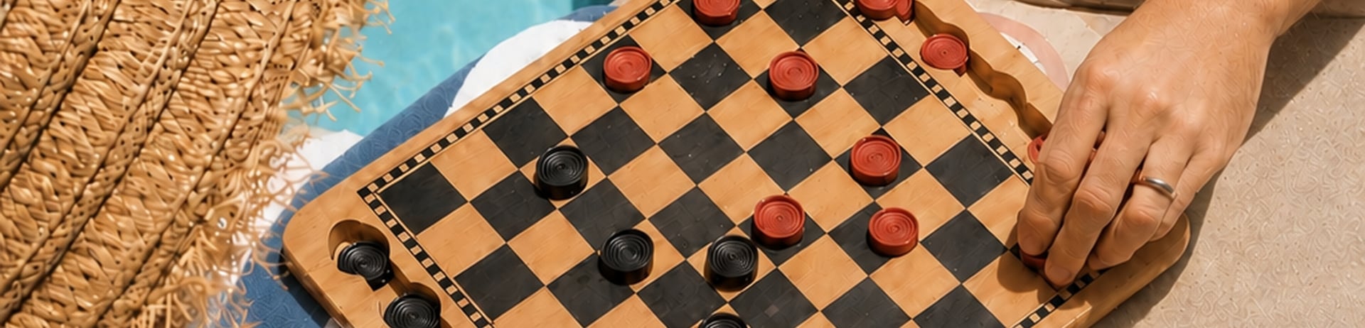Couple playing board games on the edge of a sparkling pool in summertime