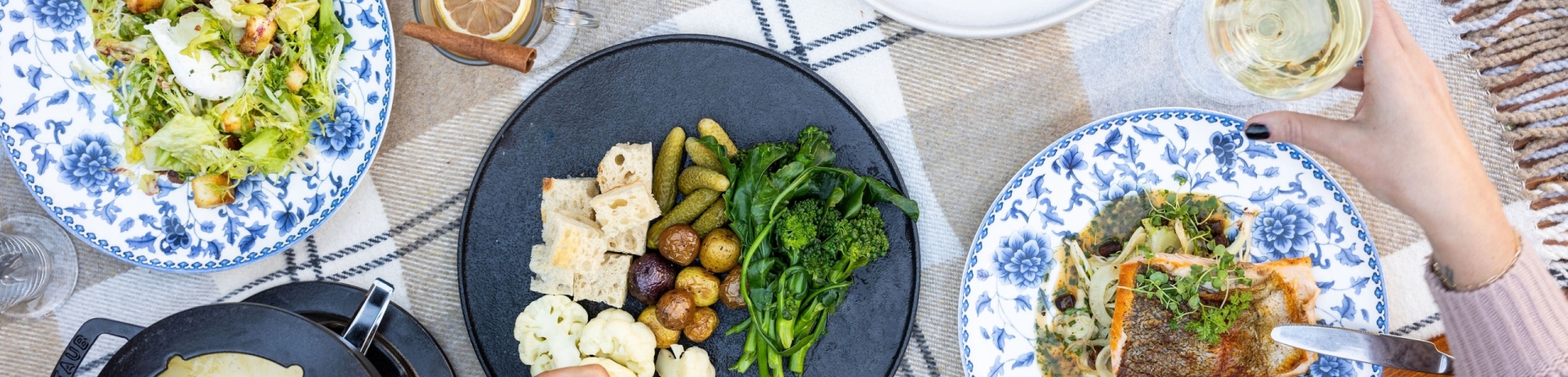 overhead photo of dining table with three people dining on cheese fondue, salad and beverages