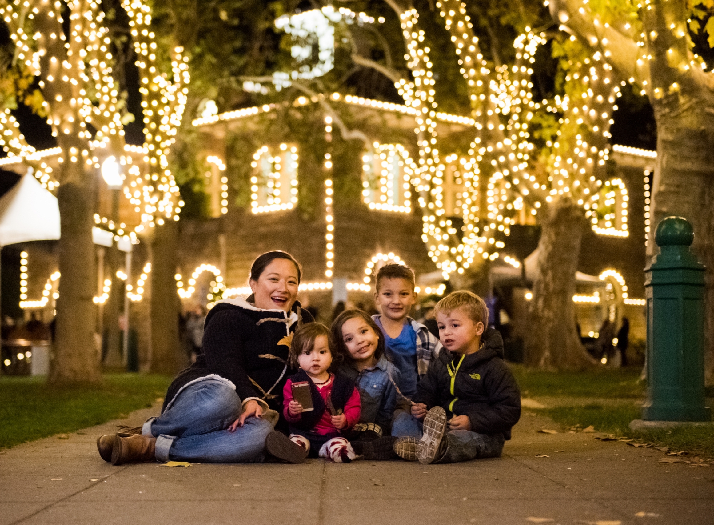 family sitting on the ground in front of a lighted brick building