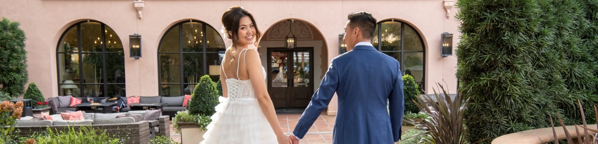 young couple walking in front of hotel on their wedding day