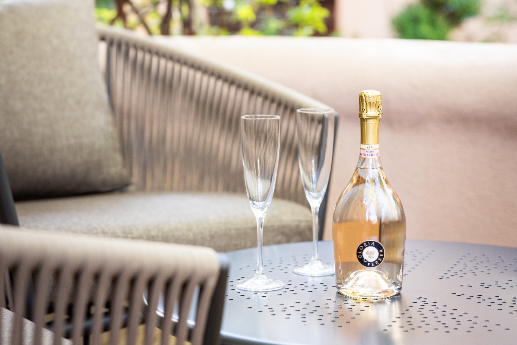 bottle of champagne and two glasses on outdoor patio table