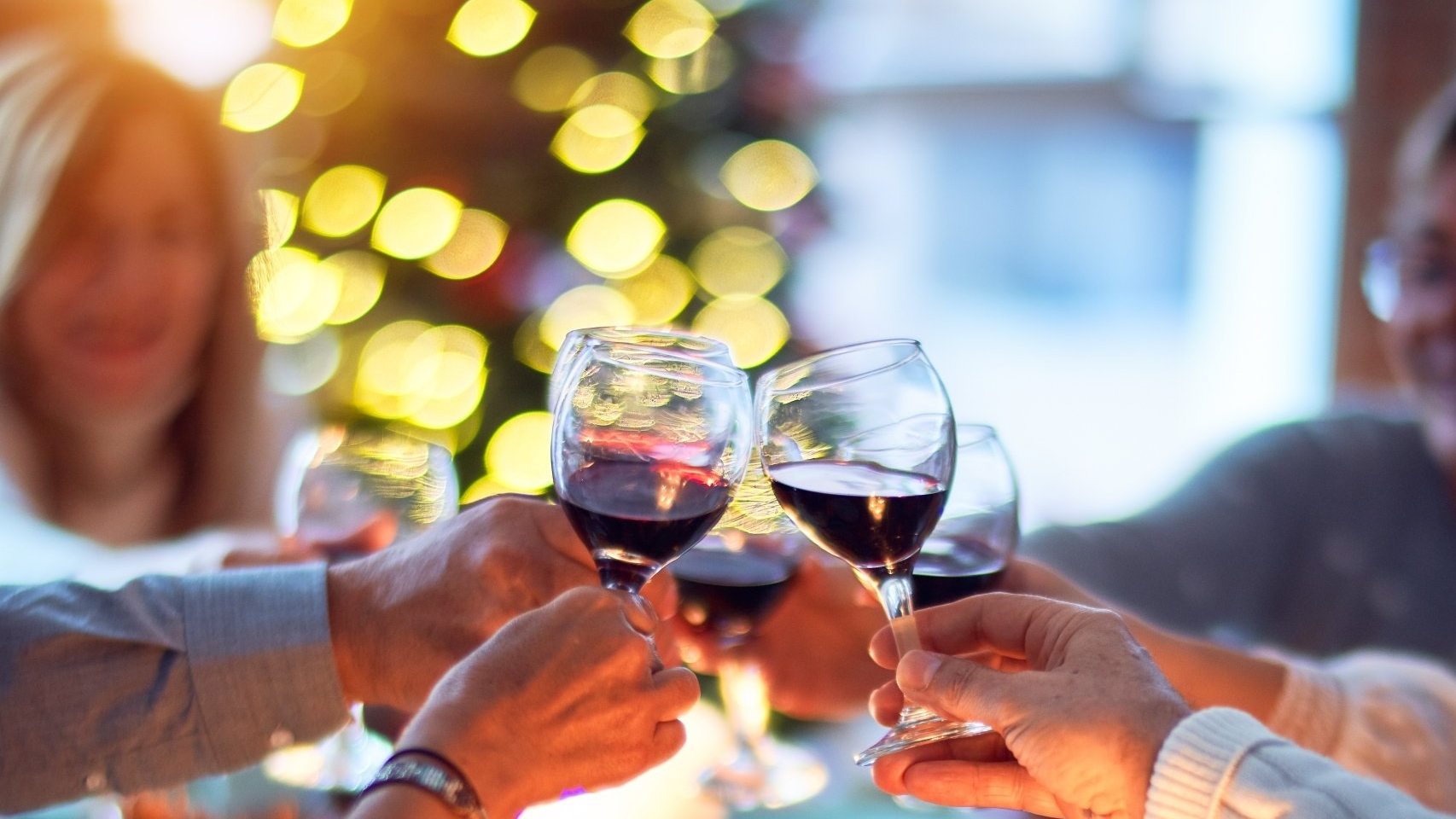 people toasting with glasses of red wine at a holiday dinner event