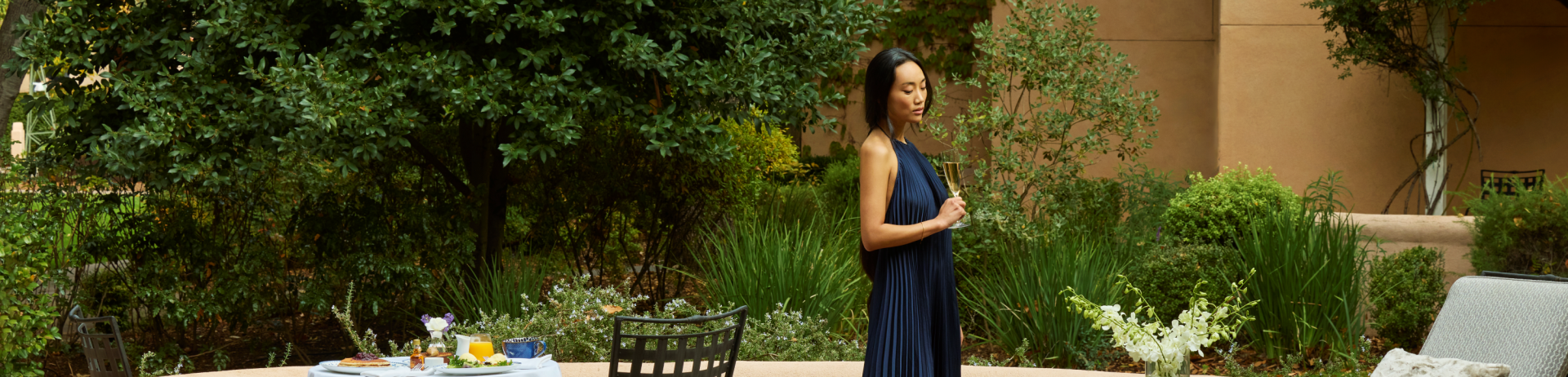 Woman in a dress standing on patio holding a champagne flute