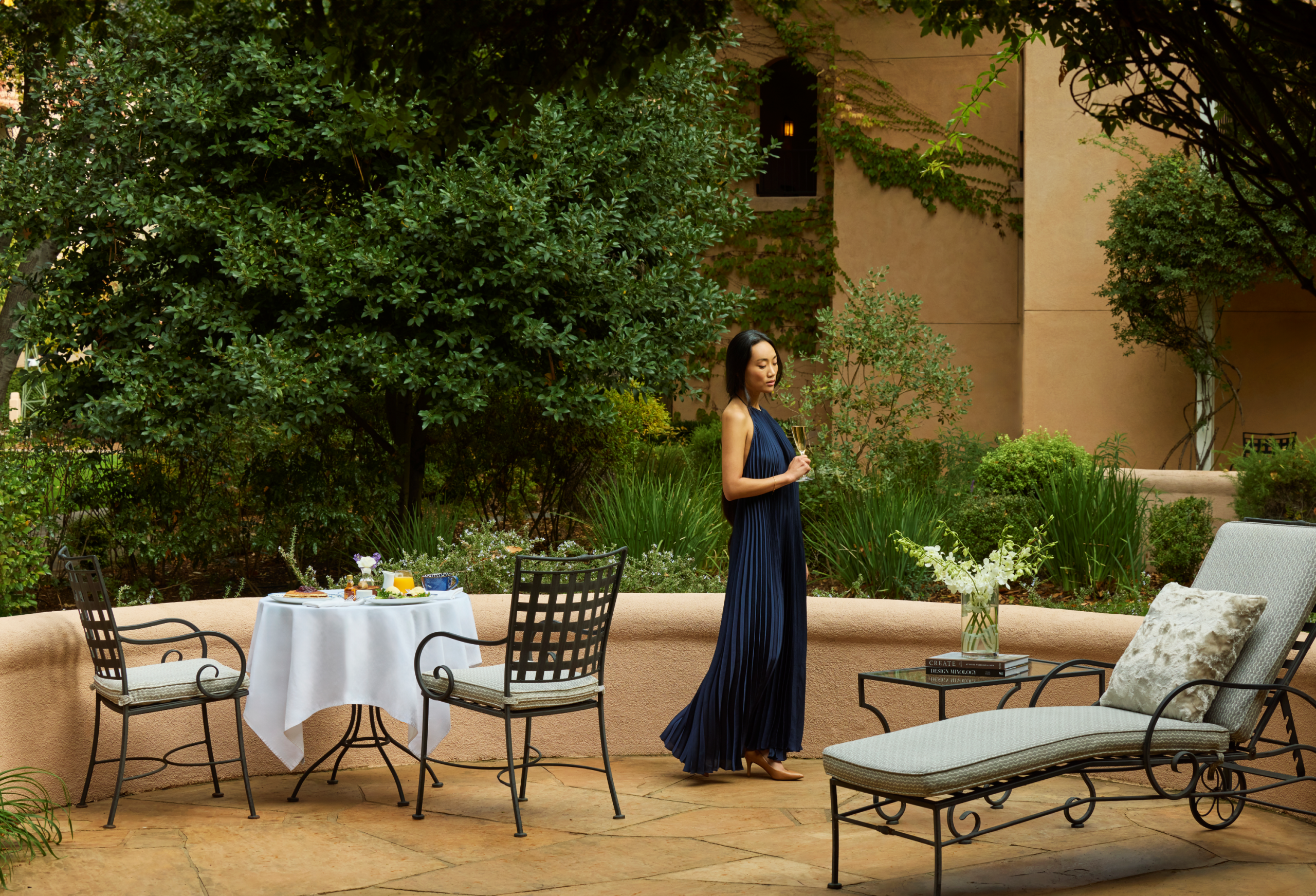 Woman in a dress standing on patio holding a champagne flute