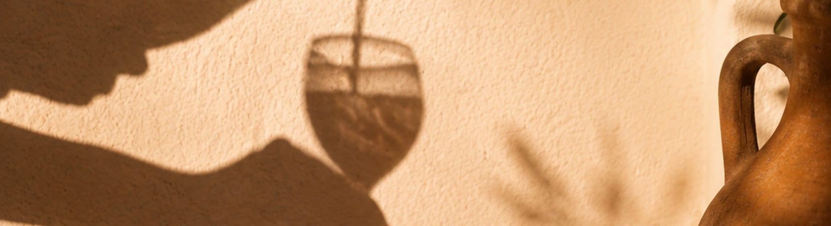 Shadow of wine being poured into a glass against a peach colored wall