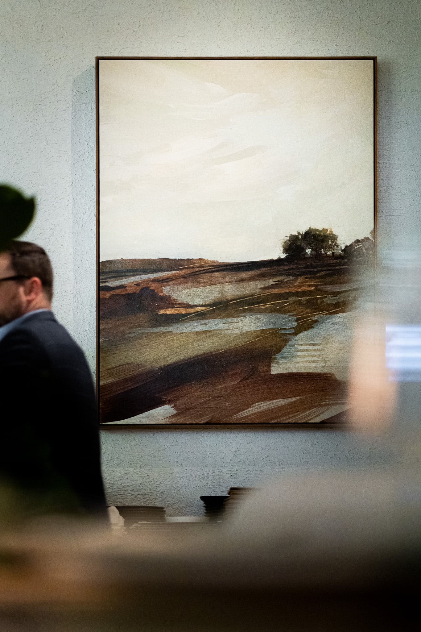 Man walking by an art piece hanging on the wall. Art courtesy of Alex Cole Studio
